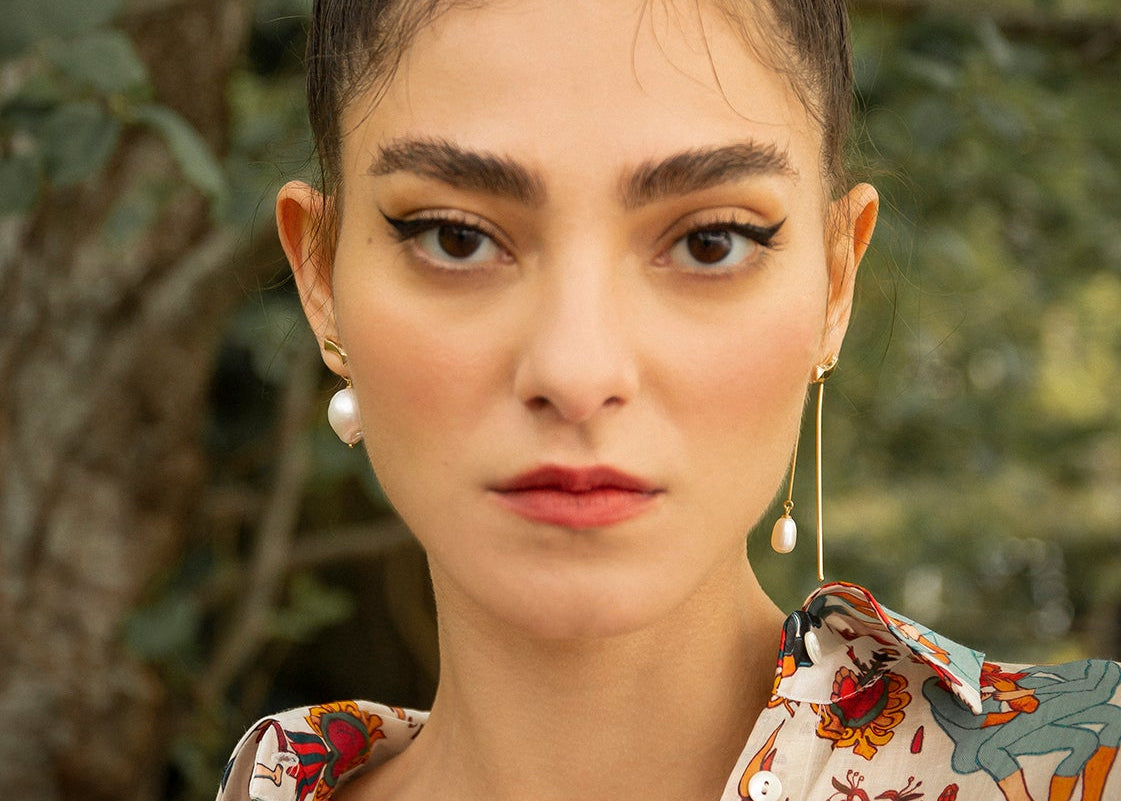 Women wearing a summer outfit with modular myoh earrings with natural pearls. Sterling silver plated gold jewelry. 